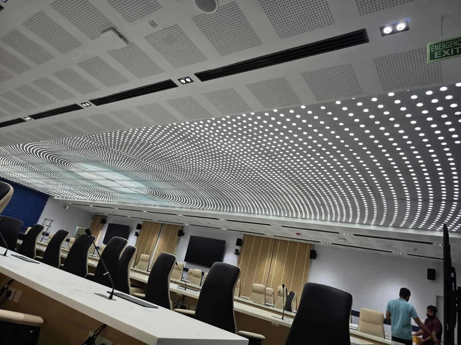 Conference auditorium with a large backlit perforated ceiling forming a radial dot pattern