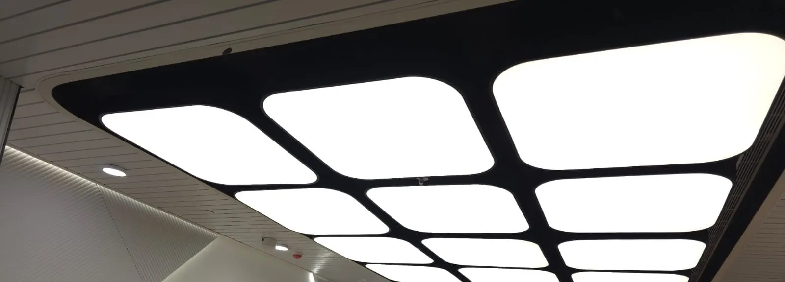 Dark ceiling bulkhead with a grid of rounded backlit white panels