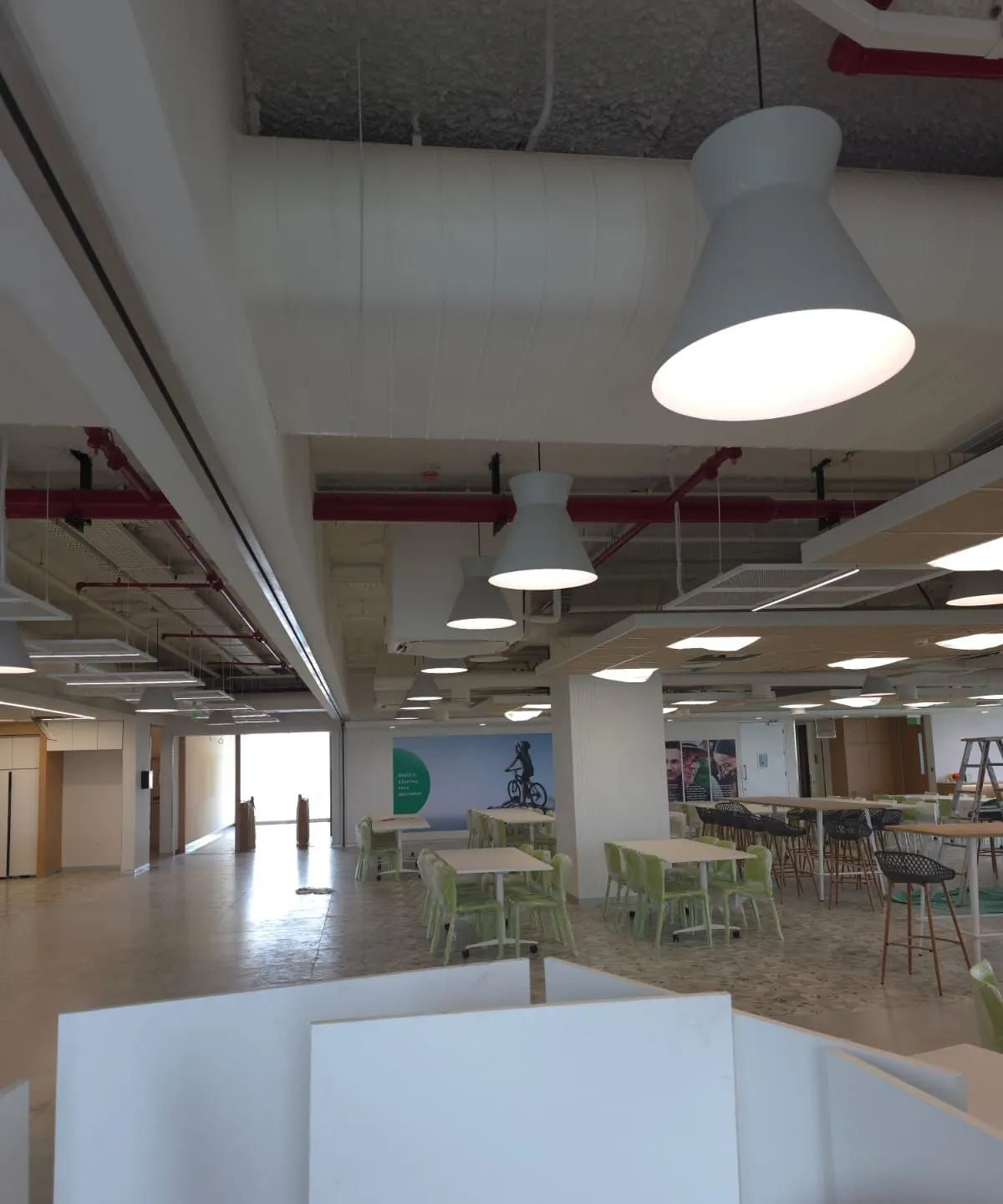 Large white cone pendants in a corporate cafeteria with an exposed ceiling