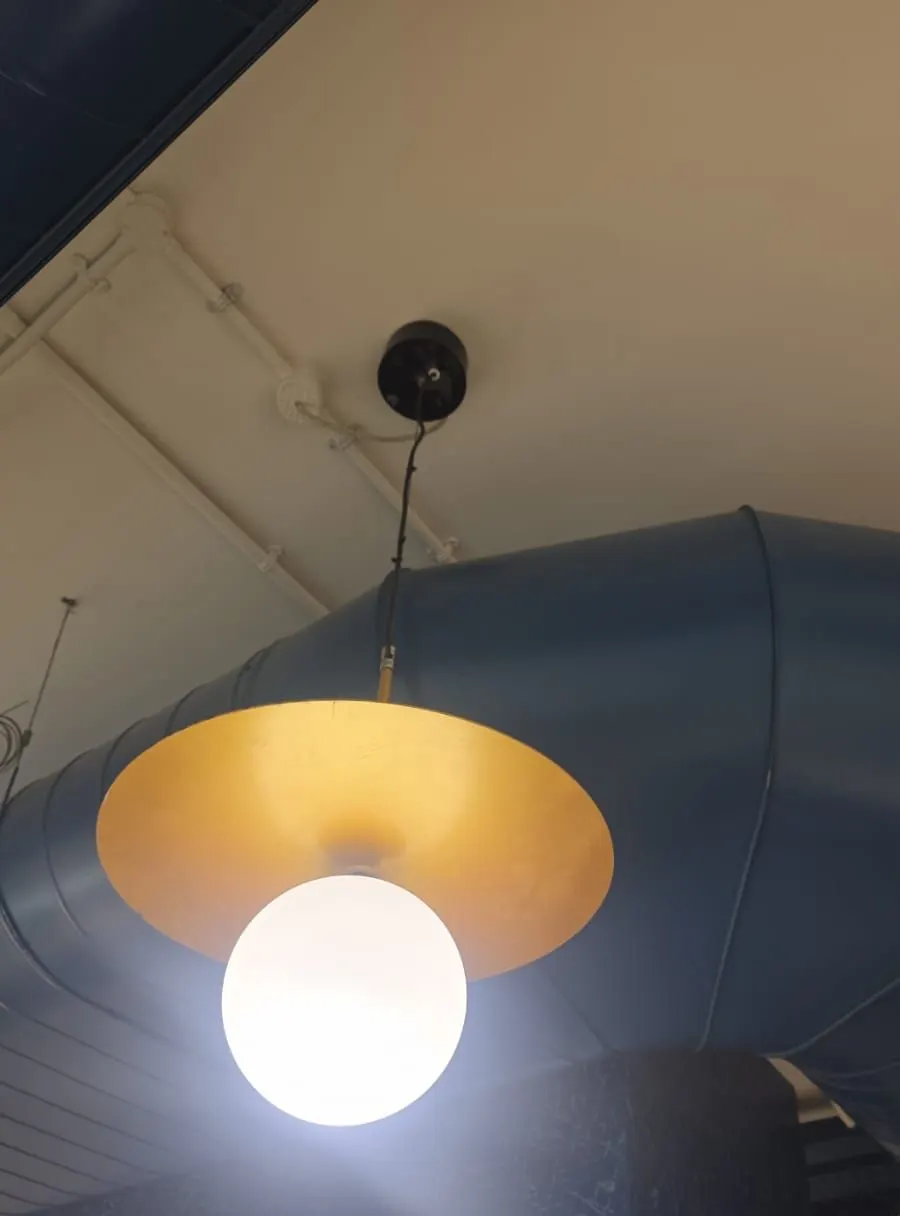 Opal globe pendant with a gold-finish dish shade under an exposed duct