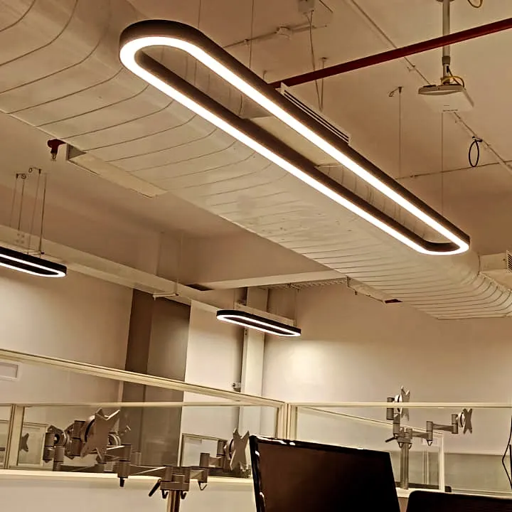Oblong suspended profile luminaire over office workstations