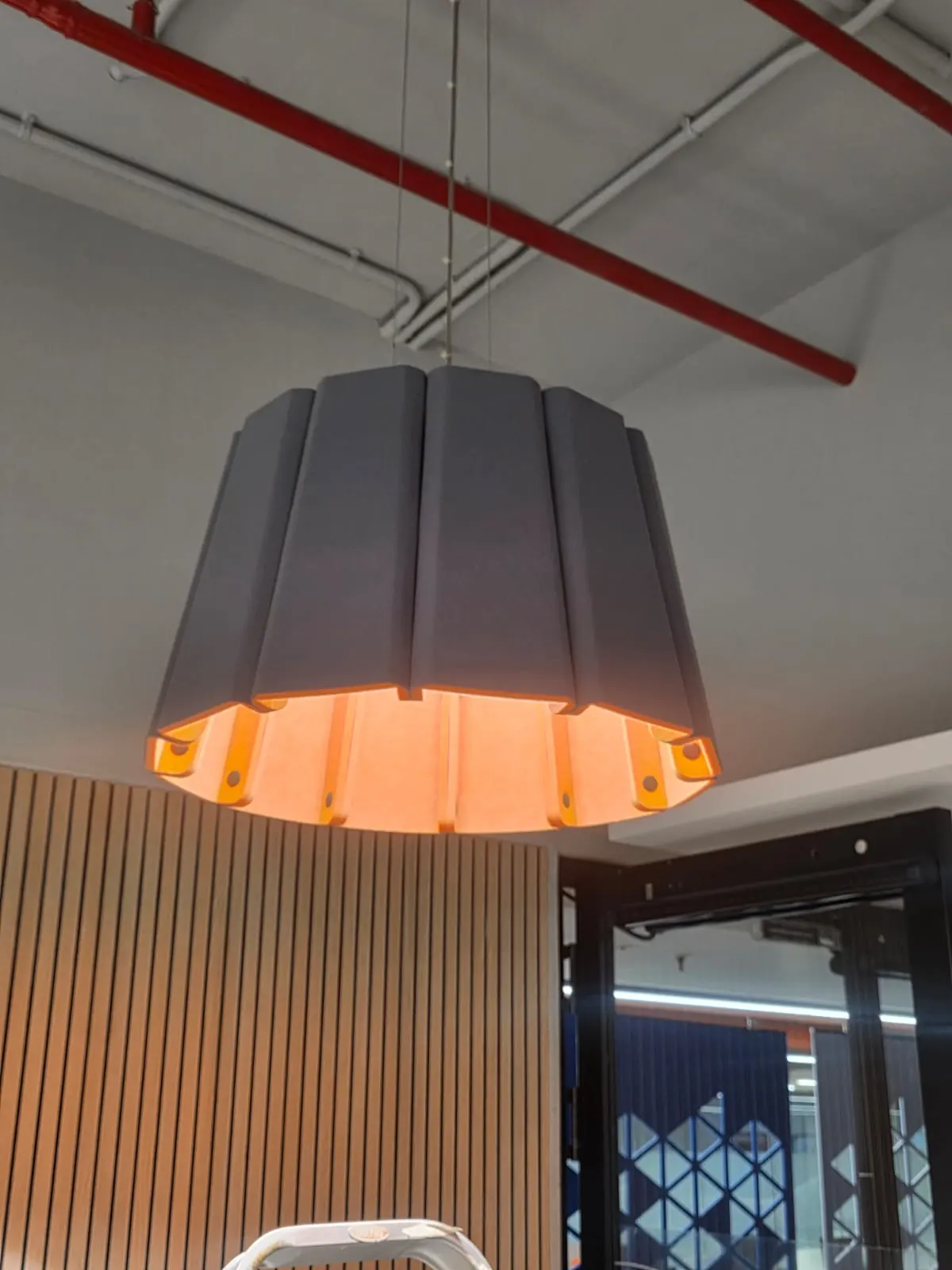 Close-up of a pleated grey fabric pendant with a warm orange interior