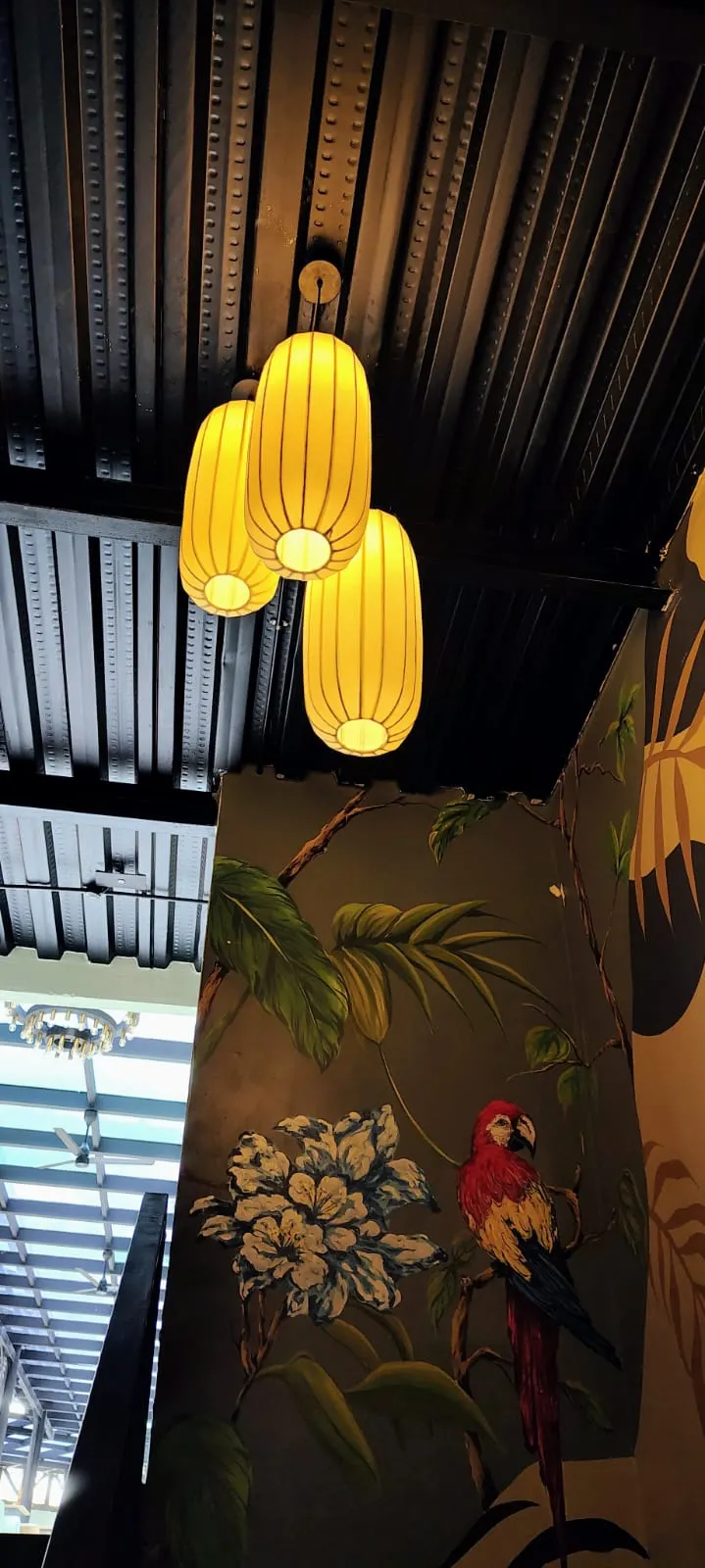 Cluster of three warm fabric lantern pendants beneath a dark metal deck ceiling