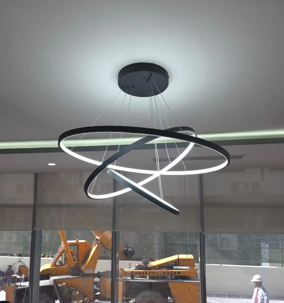 Three black illuminated rings suspended at different angles above a lounge